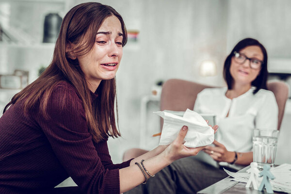 Woman holding napkins while crying and sharing her emotions
