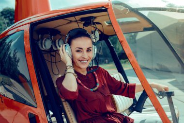 Profesyonel kulaklıklar tutan geniş gülümseme ile iyi görünümlü pilot beaming