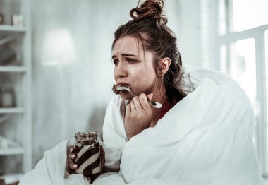 Woman eating chocolate pasta because of being stressed clipart