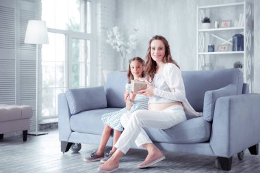 Sevimli kız oturma üzerinde kanepe yakın anne sonra veren ona küçük Present