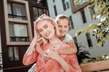 Annesinin arkasında ayakta pozitif sevimli kız