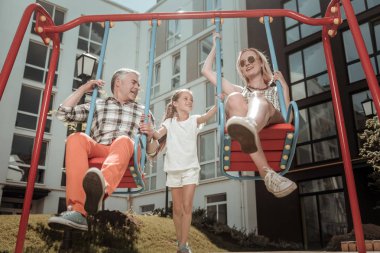 Mutlu memnun ebeveynler salıncaklar üzerinde oturuyor