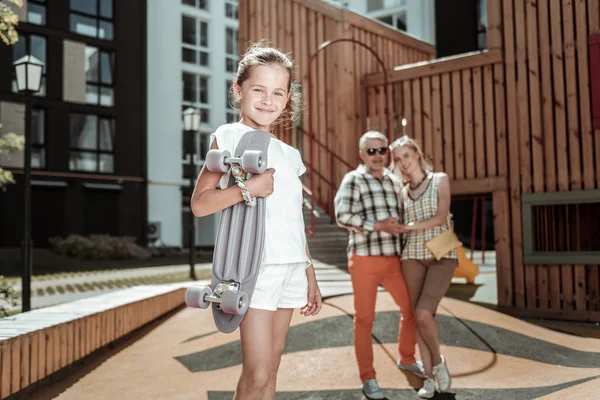 Encantado positivo bonito menina segurando um skate — Fotografia de Stock