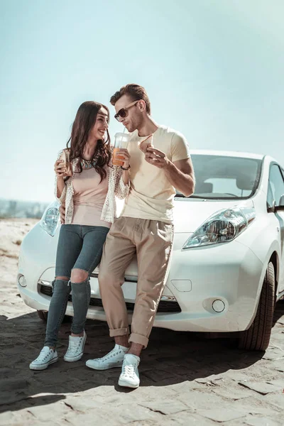 Позитивная счастливая пара, опирающаяся на свою машину — стоковое фото