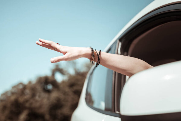 Расслабленная молодая женщина держит руку в окне
