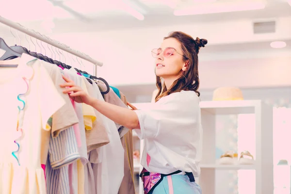 Молодая женщина выбирает яркую одежду в магазине — стоковое фото