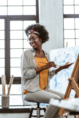 Atölyede gri tayt ve gömlek boya giyen öğrenci