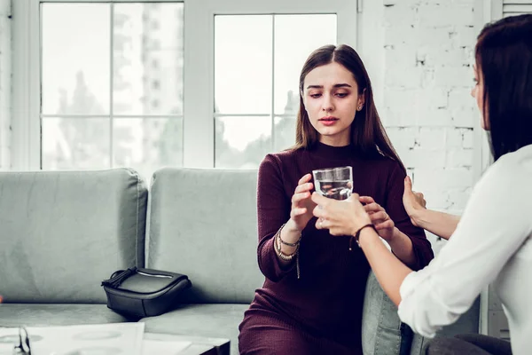 Mujer molesta tomando un vaso de agua de psicólogo de apoyo — Foto de Stock