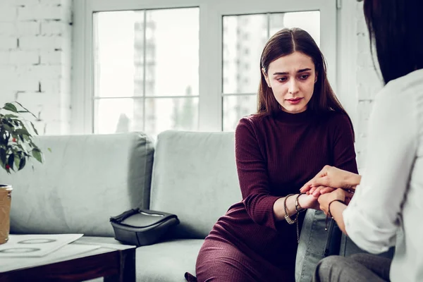 Ung upprörd kvinna sitter på soffan och lyssnar på psykolog — Stockfoto