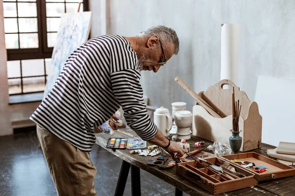 Professionell erfaren artist står nära bordet med färger — Stockfoto