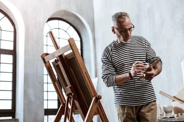 Artist wearing striped shirt feeling busy while painting still life — Stock Photo, Image