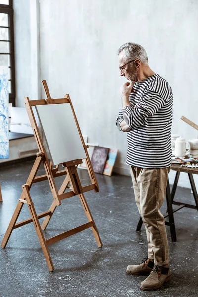Καλλιτέχνης στέκεται κοντά στο να ζωγραφίζει το καβαλέτο και σκέφτεται τι να ζωγραφίσει — Φωτογραφία Αρχείου