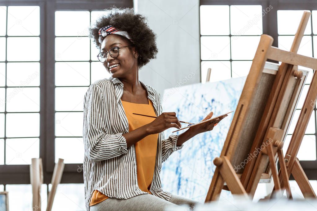Young artist feeling cheerful while having inspiration for work