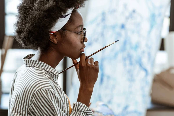 Афро-американский художник чувствует себя вдумчивым, работая над новой картиной — стоковое фото