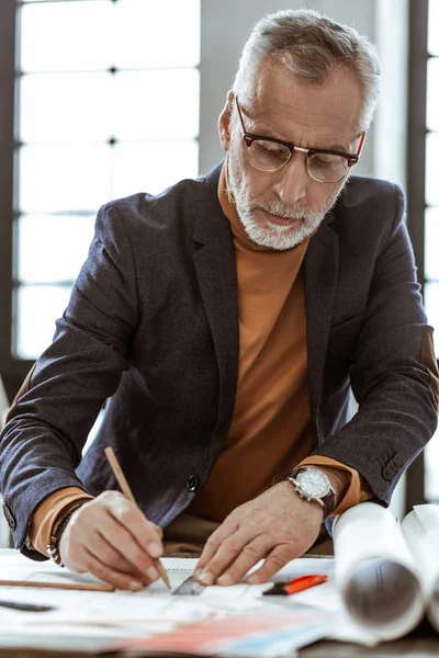 Bearded grey-haired interior designer feeling busy while working
