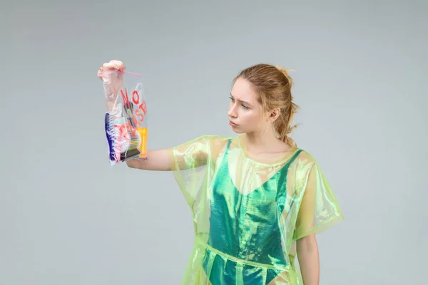 Mujer con abrigo de plástico verde mirando bolsa de plástico — Foto de Stock