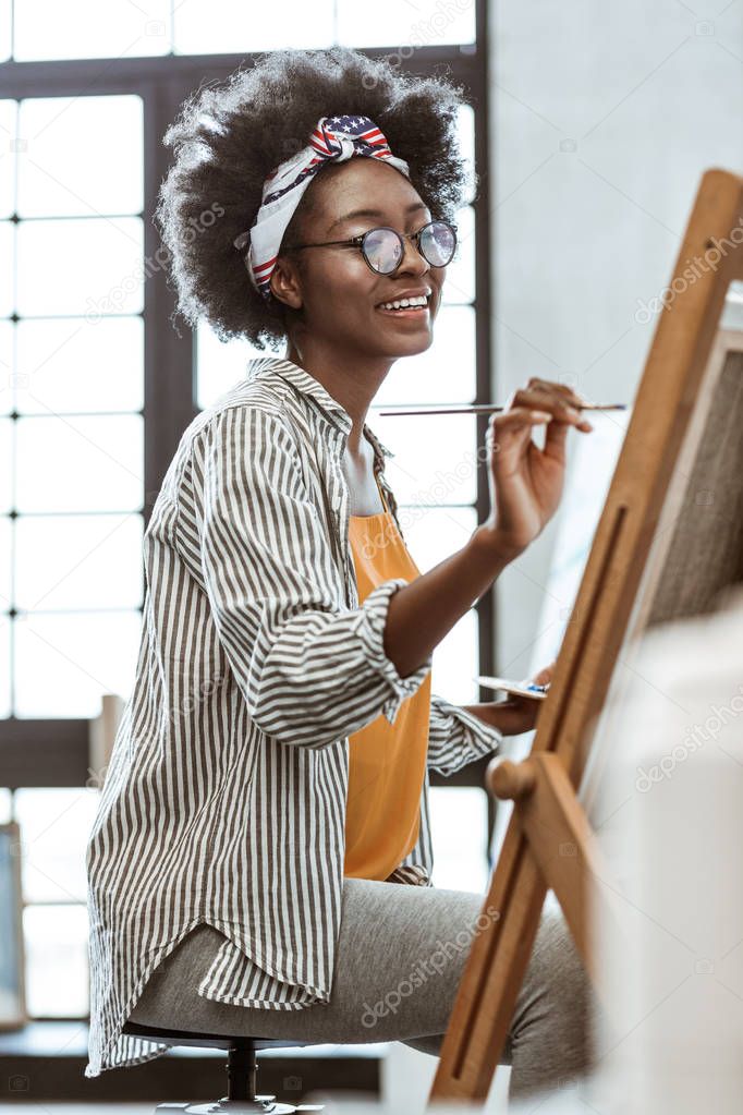 Talented artist sitting in front of drawing easel and painting