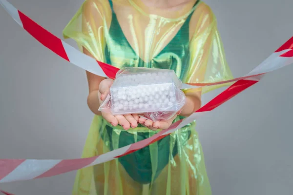 Kvinna klädd i plast klänning som håller plast påse med bomulls knoppar — Stockfoto