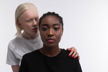 Sarışın kadın ayakta ve Afrikalı-Amerikan kadın bakıyor