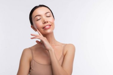 Koyu saçlı kadın bej kaşkorse gözlerini kapatmak giyiyor