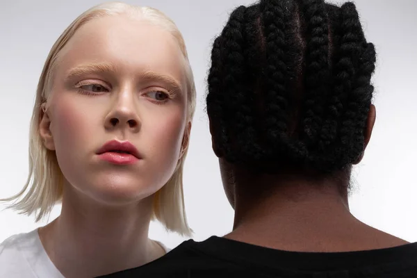 Vonzó nő szőke haja álló közel sötét bőrű személy — Stock Fotó