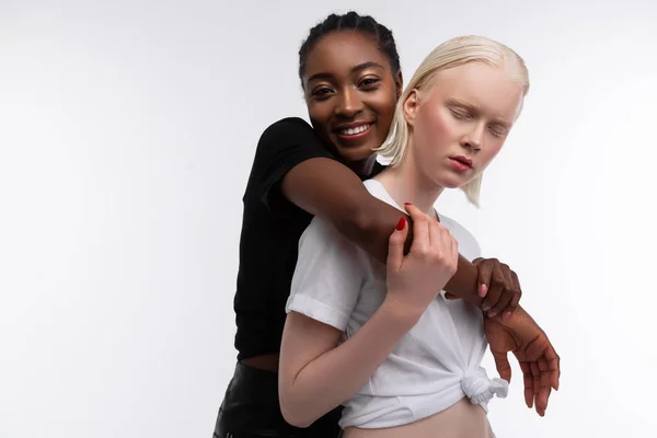 Улыбающаяся афроамериканка обнимает свою белую подругу — стоковое фото