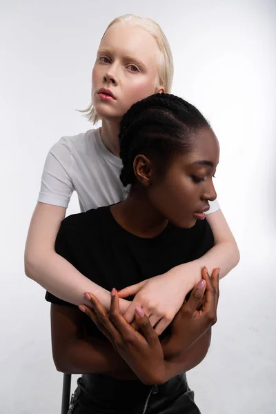 Γυναίκα αγκαλιάζει το καλύτερο σκούρο δέρμα φίλη της καθισμένος κοντά της — Φωτογραφία Αρχείου