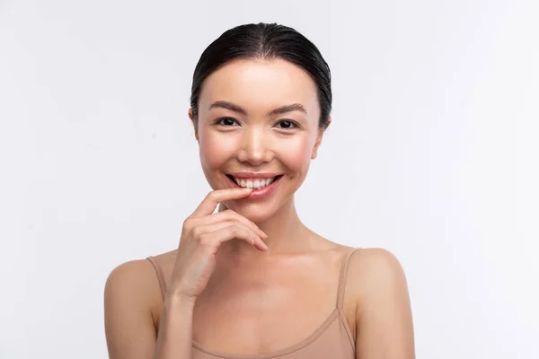 Dark-eyed woman wearing beige camisole smiling broadly — Stock Photo, Image