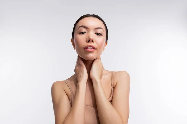 Modelo flaco con maquillaje natural tocando su cuello mientras posa — Foto de Stock