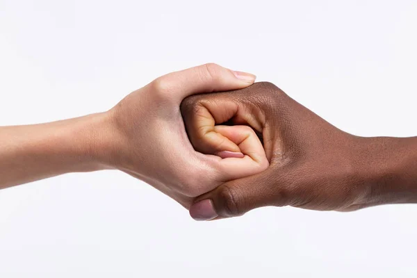 Mujeres con piel blanca estrechando la mano de su amiga de piel oscura — Foto de Stock