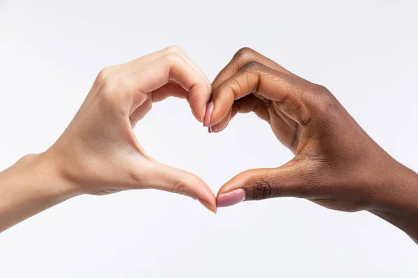 Vrouwen met witte en zwarte huid tonen hart met hun handen — Stockfoto