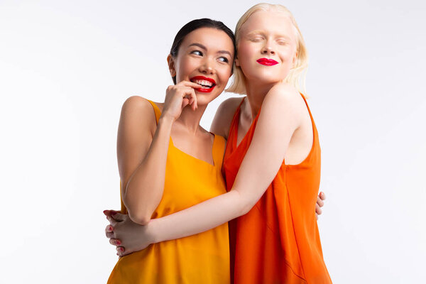 Women wearing bright dresses feeling truly happy together