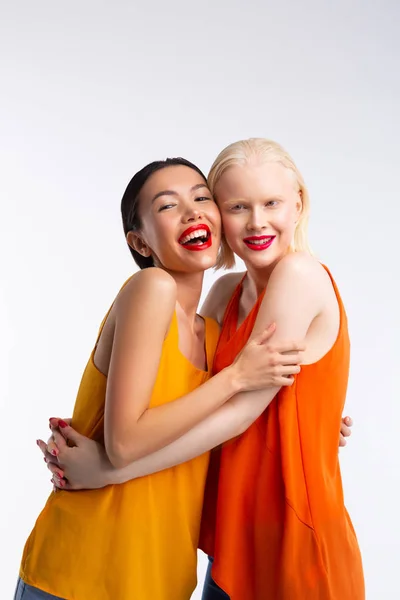 Mørkhåret kvinne som klemmer sin blonde venn, føler seg opprømt – stockfoto
