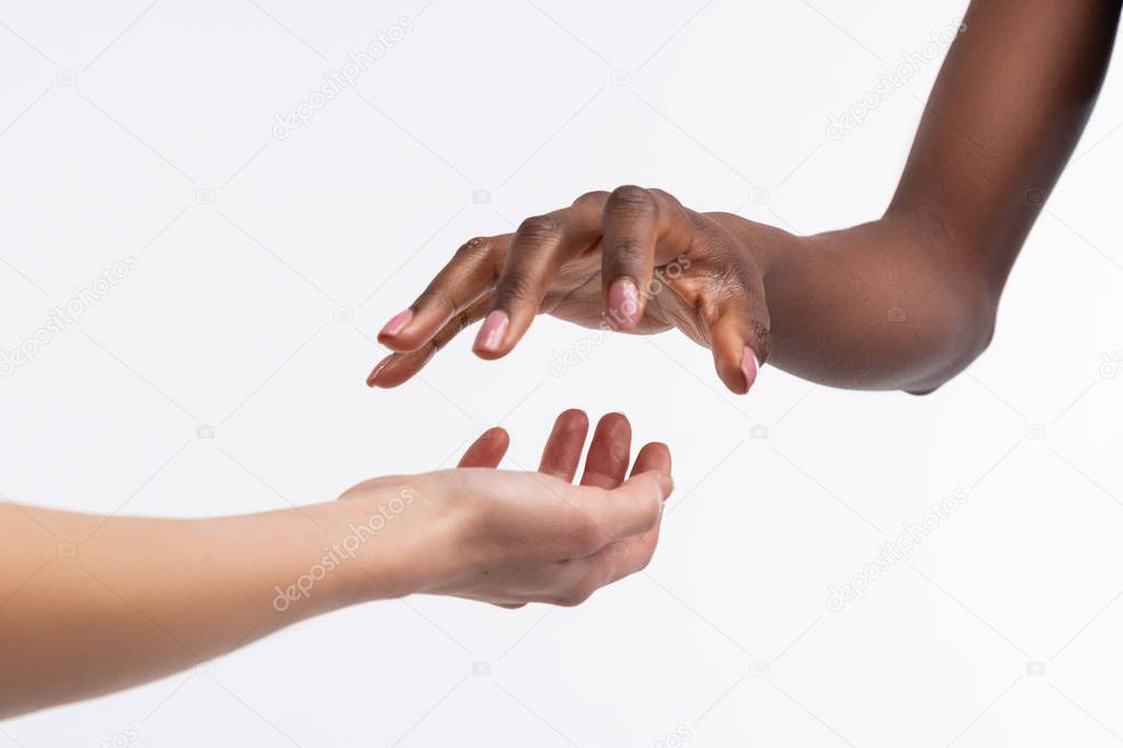 Dark-skinned woman holding her hand above white hand