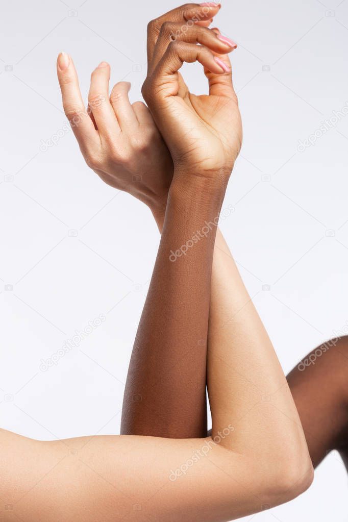 Women with different skin touching their hands and elbows