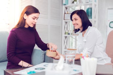 Koyu saçlı neşeli gülümseyen psikolog güzel bir üzgün hasta neşelendirme