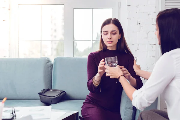 Professionelle Psychologin gibt ein Glas Wasser an verärgerte Dame. — Stockfoto