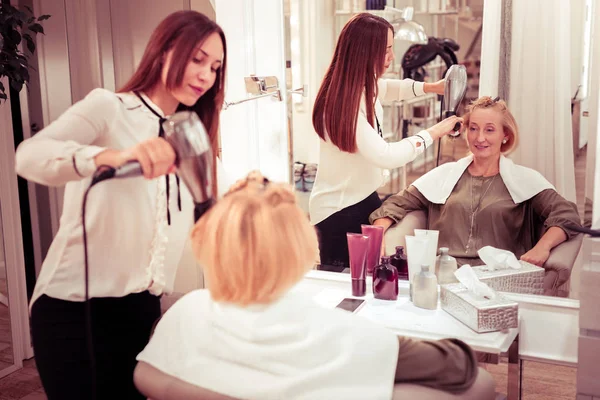 Attentive longhaired master drying hair of her client — Stock Photo, Image