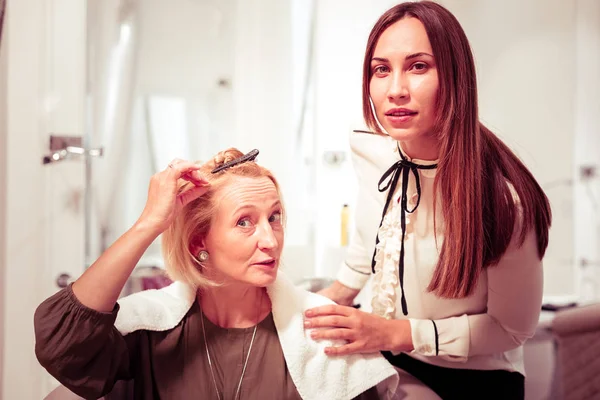 Emotional blonde female person pointing at her hair — Stock Photo, Image