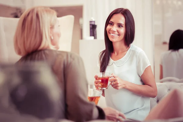 Glædelig langhåret brunette ser på hendes samtalepartner - Stock-foto