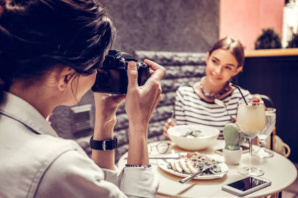 Jovem agradável segurando uma câmera de foto profissional — Fotografia de Stock