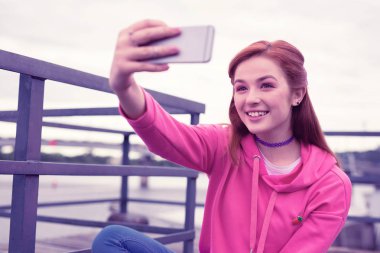 Parlak pembe kapüşonlu ve selfie yapan uzun saçlı güzel kız