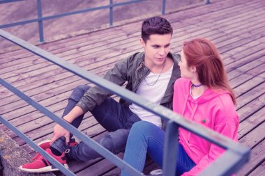 Genç, siyah saçlı adam. Hoş, kızıl kızına bakıyor.