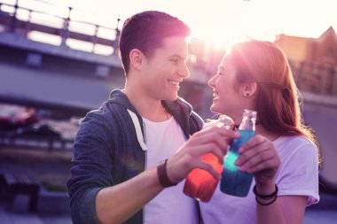 Gülen pozitif genç çift cam şişelerden ferahlatıcı soda içme