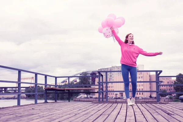 Strahlend fröhliches Mädchen in rosa Kapuzenpulli und blauer Jeans aufgeregt — Stockfoto
