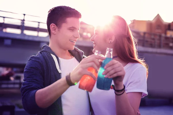 Souriant joli couple ayant des boissons fraîches dans des bouteilles en verre — Photo