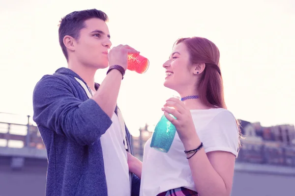 Handsome dark-haired guy drinking orange soda from glass bottle — Stock Photo, Image