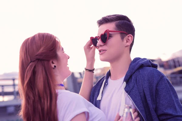 Dunkelhaariger junger Mann probiert seltsame Sonnenbrille in Herzform an — Stockfoto