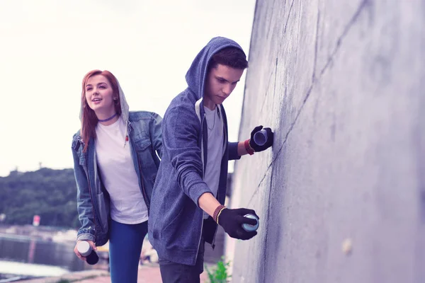 Inspired dark-haired guy being graffiti artist and painting concrete surface — Stock Photo, Image