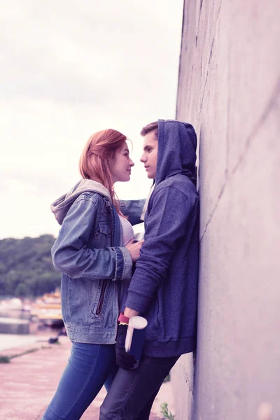 Romantyczna Młoda para wyrażająca swoje uczucia podczas przytulania w pobliżu ściany — Zdjęcie stockowe